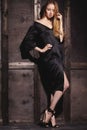 Fashion portrait of beautiful young woman in black dress near with wood wall. Elegant dark evening look