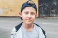 Fashion portrait of caucasian blue-eyed blonde hair 13-year-old skateboarder teenager boy in a baseball cap. Youth generation