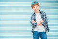 Fashion portrait of caucasian blue-eyed blonde hair 12 year old teenager boy dressed t-shirt and checkered shirt with sunglasses