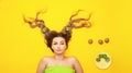 Fashion portrait of cheerful girl on colored background with kiwi slices on long hair, people and food, young funny woman head Royalty Free Stock Photo