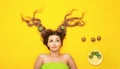 Fashion portrait of cheerful girl on colored background with kiwi slices on long hair, people and food, young funny woman head Royalty Free Stock Photo