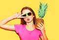 Fashion portrait cool girl in sunglasses and pineapple over yellow