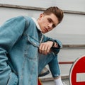 Fashion Portrait Cool Young Man With Hairstyle In Blue Youth Casual Jeans Clothes Near Metal Road Sign