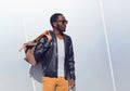 Fashion portrait elegant african man wearing a sunglasses and black rock leather jacket with bag in the city, copy space empty Royalty Free Stock Photo