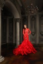 Fashion portrait of elegant attractive model woman in red dress in luxurious dark vintage interior Royalty Free Stock Photo