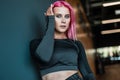 Fashion portrait of a fitness girl with pink hair in black sportswear on a dark background in the gym Royalty Free Stock Photo