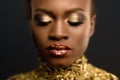 Fashion Portrait of Glossy African American Woman with Bright Golden Makeup. Bronze Bodypaint, Black Studio Background