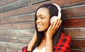 Fashion portrait happy smiling african woman with headphones is enjoying listens to music over background Royalty Free Stock Photo