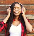 Fashion portrait of happy smiling young african woman with headphones enjoying listens to music Royalty Free Stock Photo