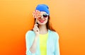 Fashion portrait happy smiling young woman is closes her eye with a lollipop on stick over colorful orange Royalty Free Stock Photo