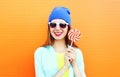 Fashion portrait happy smiling young woman is holds a lollipop on stick over colorful orange Royalty Free Stock Photo