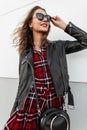 Fashion portrait happy woman with sexy red lips with smile in glasses in casual youth clothes with black leather bag near wall Royalty Free Stock Photo