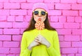 Fashion portrait pretty cool girl with lollipop over colorful pink Royalty Free Stock Photo