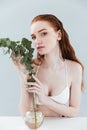 Fashion portrait of a pretty sensual redheaded woman holding eucaliptus