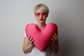 Fashion portrait pretty sweet young woman with red lips hugging a plush heart wearing white tshort over white background Royalty Free Stock Photo