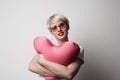 Fashion portrait pretty sweet young woman with red lips hugging a plush heart wearing white tshort over white background Royalty Free Stock Photo