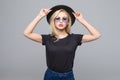 Fashion portrait pretty sweet young woman wearing a black hat sunglasses over grey background Royalty Free Stock Photo