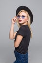 Fashion portrait pretty sweet young woman wearing a black hat sunglasses over grey background Royalty Free Stock Photo