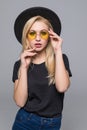 Fashion portrait pretty sweet young woman wearing a black hat sunglasses over grey background Royalty Free Stock Photo