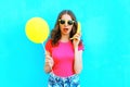 Fashion portrait pretty woman with banana and yellow a air balloon having fun over colorful blue background