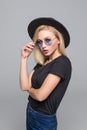 Fashion portrait pretty sweet young woman wearing a black hat sunglasses over grey background Royalty Free Stock Photo