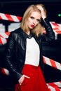 Fashion portrait of blonde girl with red lips wearing a rock black style posing on the background of warning tape. Royalty Free Stock Photo