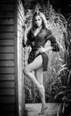 Fashion portrait of brunette in black swimsuit leaning on wooden cabin wall. Sensual attractive woman with long legs Royalty Free Stock Photo