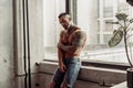 Fashion portrait of naked male model with tattoo and a black beard standing in hot pose on near the window. Loft room interio Royalty Free Stock Photo