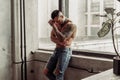 Fashion portrait of naked male model with tattoo and a black beard standing in hot pose on near the window. Loft room interio Royalty Free Stock Photo