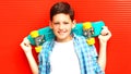 Fashion portrait smiling teenager boy with skateboard on red Royalty Free Stock Photo