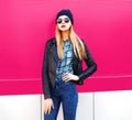 Fashion portrait stylish blonde woman in rock black style jacket, hat posing on city street over colorful pink wall Royalty Free Stock Photo