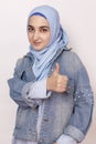 Fashion portrait of stylish Muslim girl in jean jacket giving thumbs up. Modern and young middle-eastern girl in hijab with denim