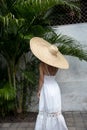 Fashion portrait of stylish woman wearing white dress and large big giant straw