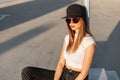 Fashion portrait urban woman with sexy lips in white stylish torn top in jeans in cool trendy sunglasses and black baseball cap