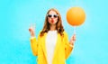 Fashion portrait woman holds orange air balloon in yellow coat