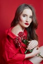 Fashion portrait of woman in red dress, beautiful makeup, curly long hair. Girl perfect lip makeup on red background Royalty Free Stock Photo