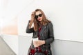 Fashion portrait woman in trendy red-black youth clothes from new collection with cup tea or coffee rest near modern wall on Royalty Free Stock Photo