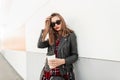 Fashion portrait woman in trendy red-black youth clothes from new collection with cup tea or coffee rest near modern wall on Royalty Free Stock Photo