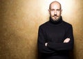 Fashion Portrait of 40-year-old man standing over light gold background in a black sweater. Close up. Classic style. Bald shaved Royalty Free Stock Photo