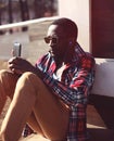 Fashion portrait young african man listens to music using smartphone Royalty Free Stock Photo