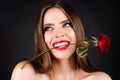 Fashion portrait of young beautiful woman with red rose on black background. Rose flowers in a mouth. Sensual woman Royalty Free Stock Photo