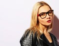 Fashion portrait of young blond woman. Black leather jacket, pants and glasses. Royalty Free Stock Photo