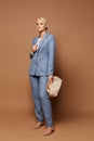 A fashion portrait of a young business lady in an elegant blue suit posing with stylish purse on the beige background Royalty Free Stock Photo