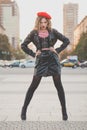 Fashion portrait of young woman in black leather jacket and red beret posing on the street Royalty Free Stock Photo