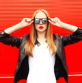 Fashion portrait young woman wearing a rock black jacket and sunglasses over red Royalty Free Stock Photo