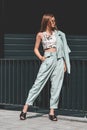 Fashion portrait of young woman wearing sunglasses, top, slingbacks, blue suit. Young beautiful happy model posing near