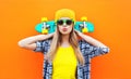 Fashion pretty cool girl with skateboard over colorful orange Royalty Free Stock Photo