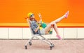 Fashion pretty cool girl in trolley cart having fun over colorful orange Royalty Free Stock Photo