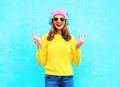 Fashion pretty cool smiling girl in headphones listening to music wearing a colorful pink hat yellow sunglasses and sweater Royalty Free Stock Photo