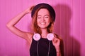 Fashion pretty cool woman in hat and headphones listening to music over pink neon background. Beautiful young teenage girl in hat Royalty Free Stock Photo